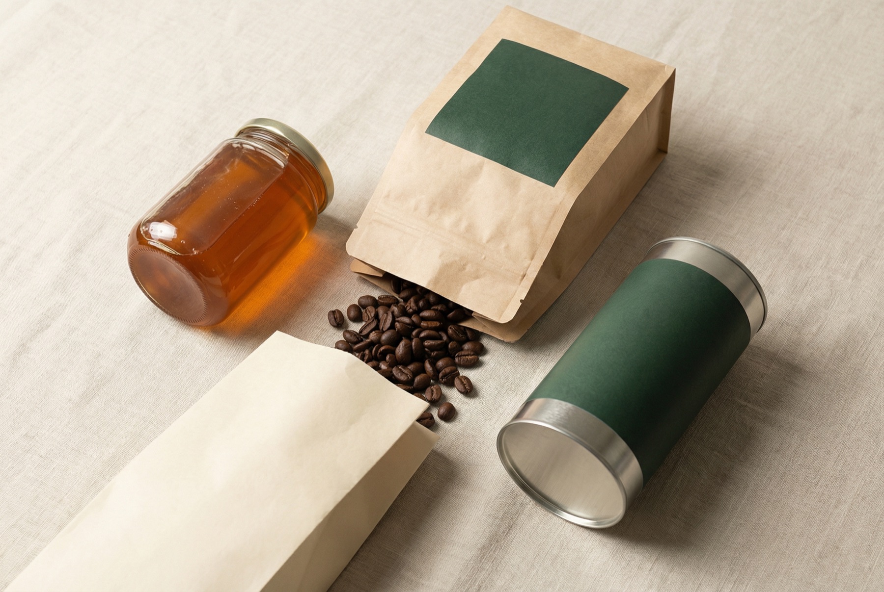 Minimalist still life of craft CPG packaging — honey jar, coffee, olive oil tin
